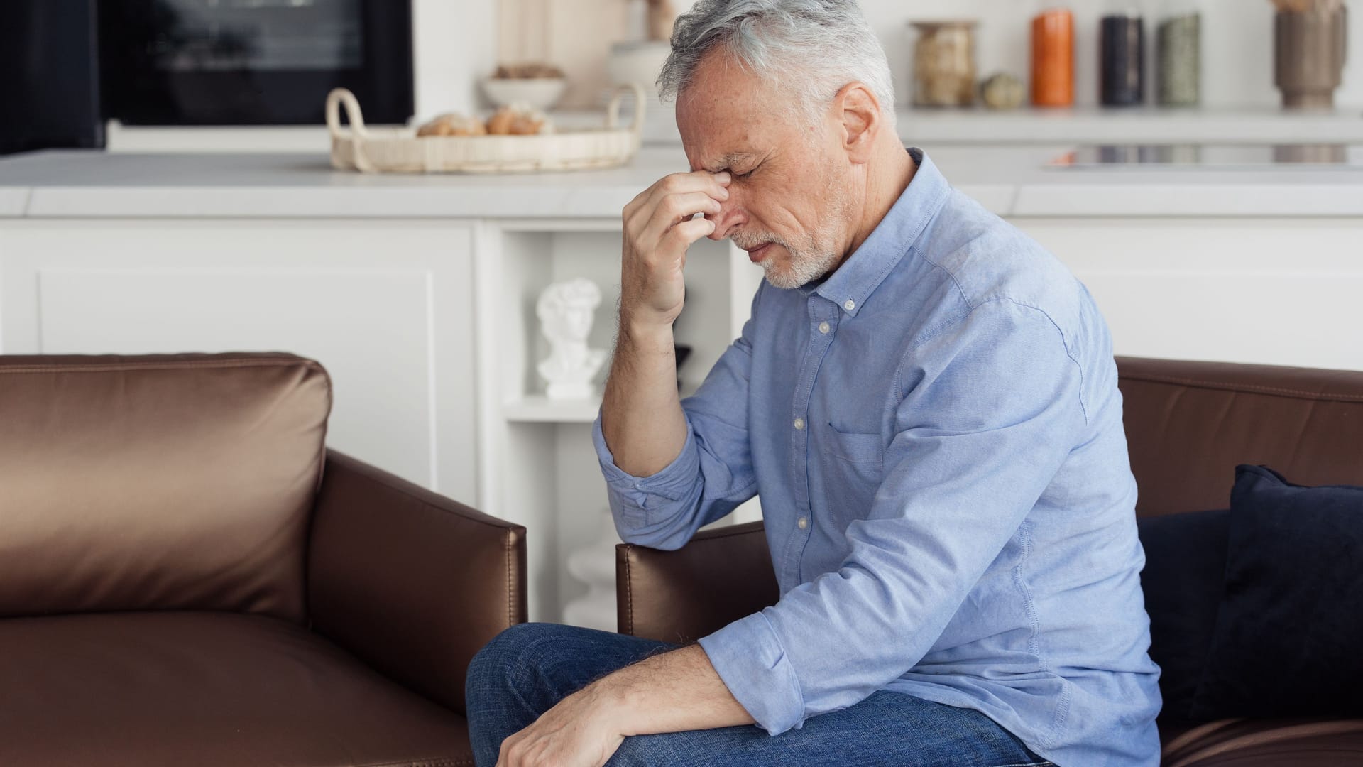 Ein Mann sitzt auf dem Sofa und leidet an Kreislaufproblemen