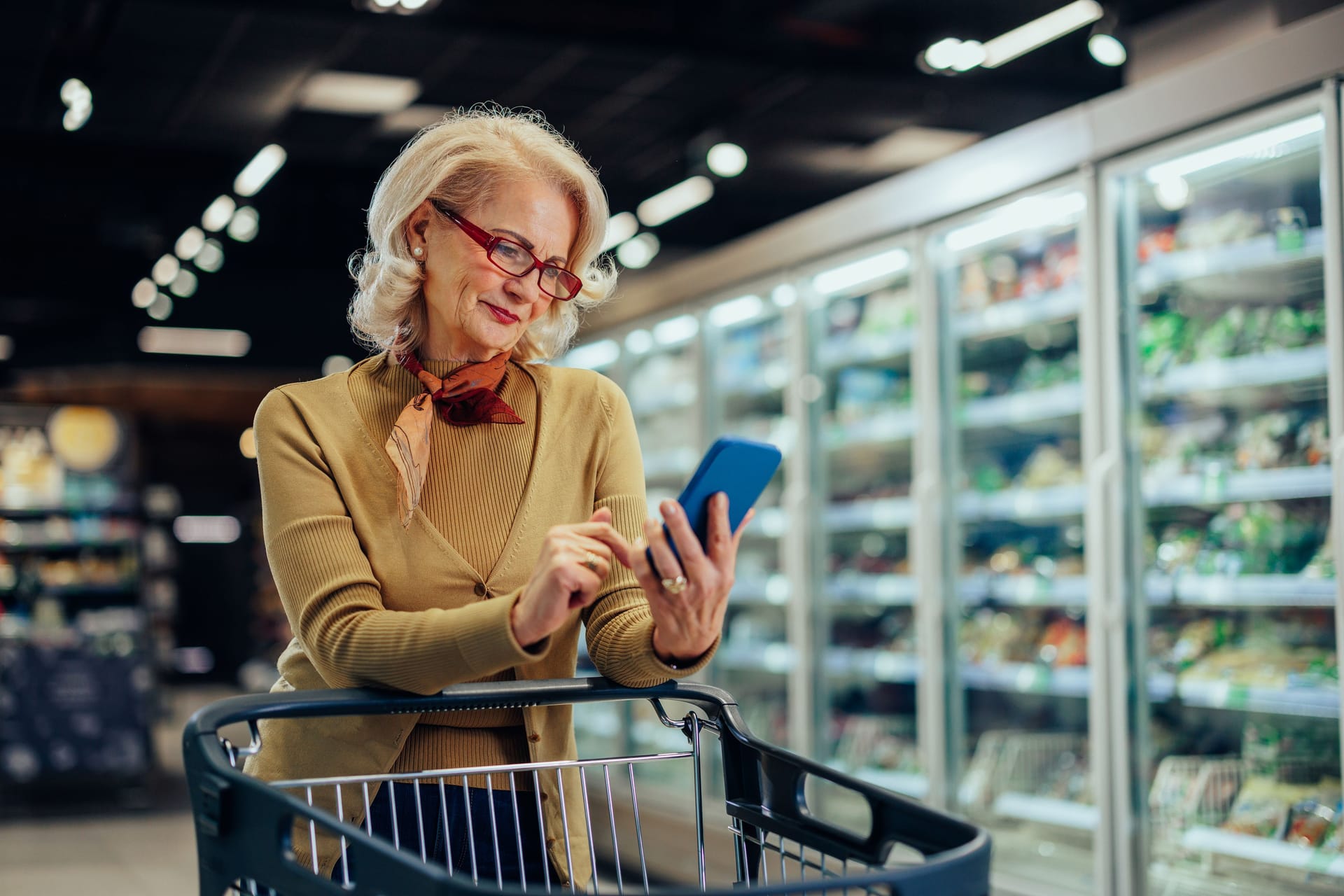 Frau im Supermarkt schaut auf ihr Handy