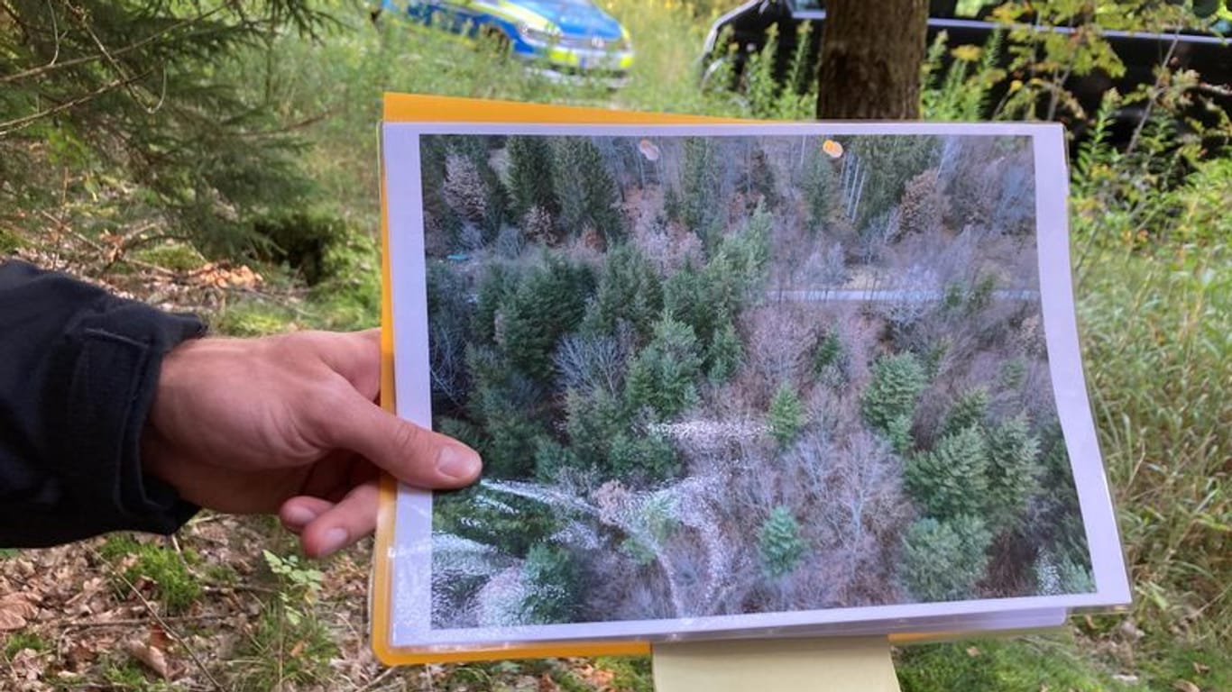 Polizeibeamter mit Drohnen-Bild im Wald: Die Auswertung der Aufnahmen aus der Luft lieferte 114 Orte, an denen die Beamten noch einmal genau nachschauen wollen.