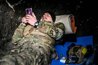 Ein ukrainischer Soldat schaut auf sein Handy (Symbolbild). Viele nutzen die Geräte zum Spielen, berichtet die "New York Times".