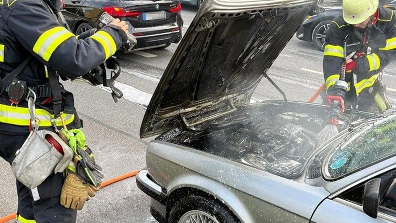Einsatzkräfte der Feuerwehr München löschen den in Brand geratenen BMW.