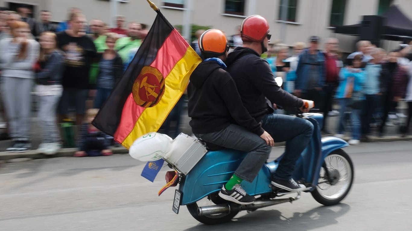Teilnehmer des Festumzuges beim Tag der Sachsen mit DDR-Fahne auf einem Moped der Marke „Schwalbe“.