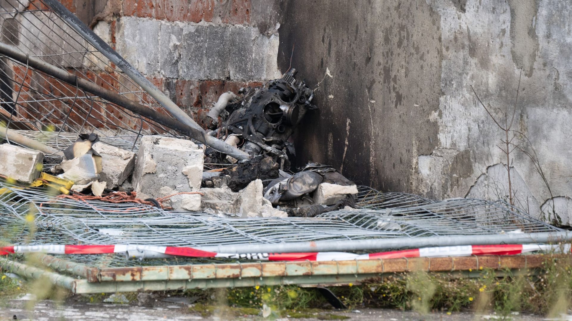 Wrackteile liegen nach dem Absturz eines Kleinflugzeug auf eine Lagerhalle hinter einer Polizeiabsperrung. Bei den Absturz kam der Pilot als einziger Insasse ums Leben.
