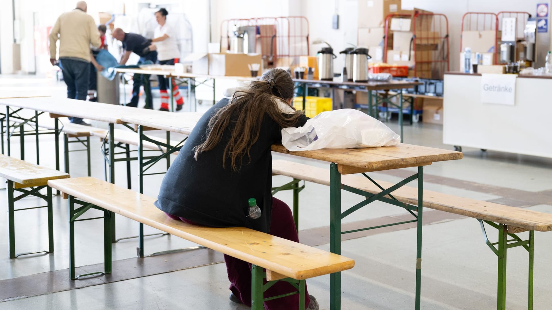 Eine Frau sitzt in der Messe Dresden in einer Notunterkunft an einer Biertischgarnitur. Die Vorbereitungen für einen weiteren Versuch zum Entschärfen einer Weltkriegsbombe sind abgeschlossen. Rund 2700 Menschen sind nach Angaben der Polizei von der damit zusammenhängenden Evakuierung betroffen.