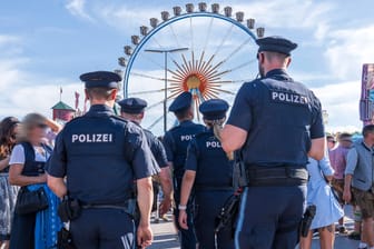 Mehrere Polizisten stehen vor dem Riesenrad auf der Wiesn (Symbolbild): Für eine ihrer Kolleginnen gab's in luftiger Höhe eine Überraschung.