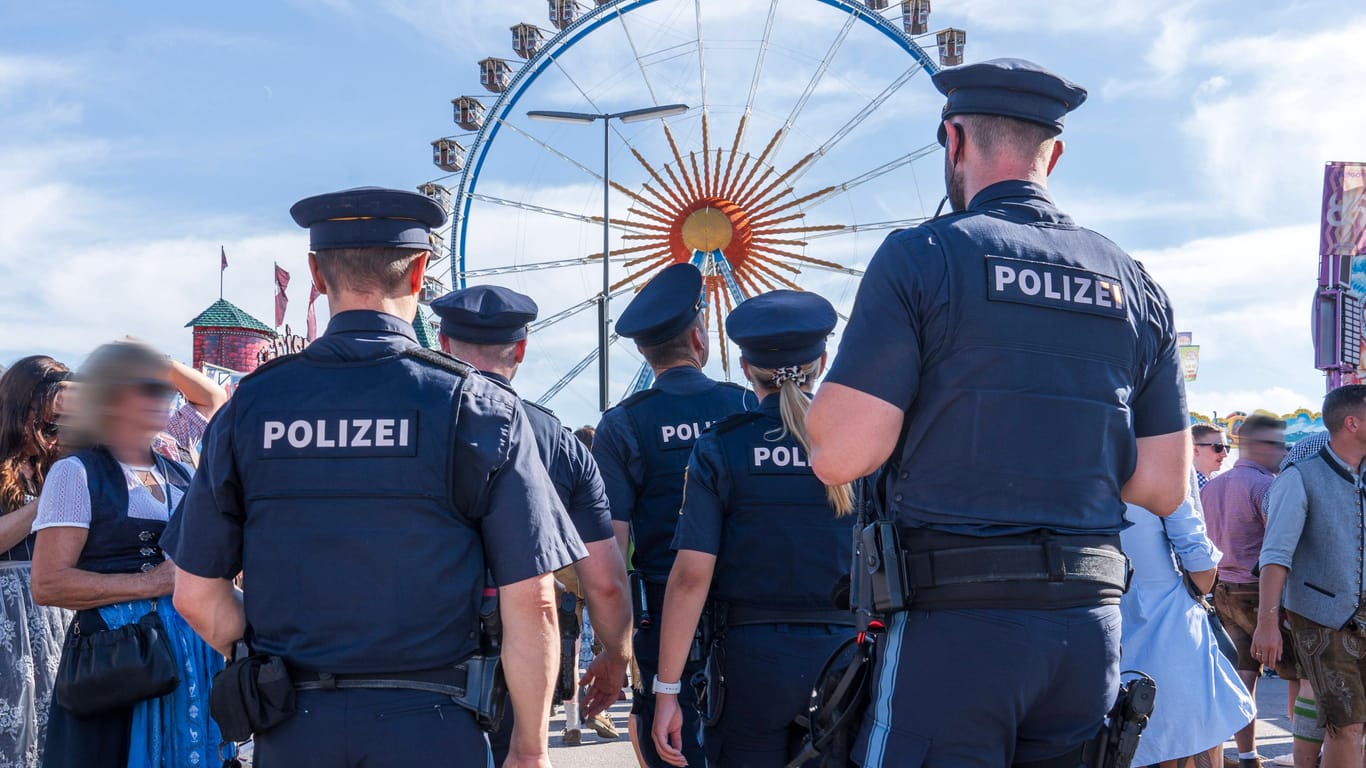 Mehrere Polizisten stehen vor dem Riesenrad auf der Wiesn (Symbolbild): Für eine ihrer Kolleginnen gab's in luftiger Höhe eine Überraschung.
