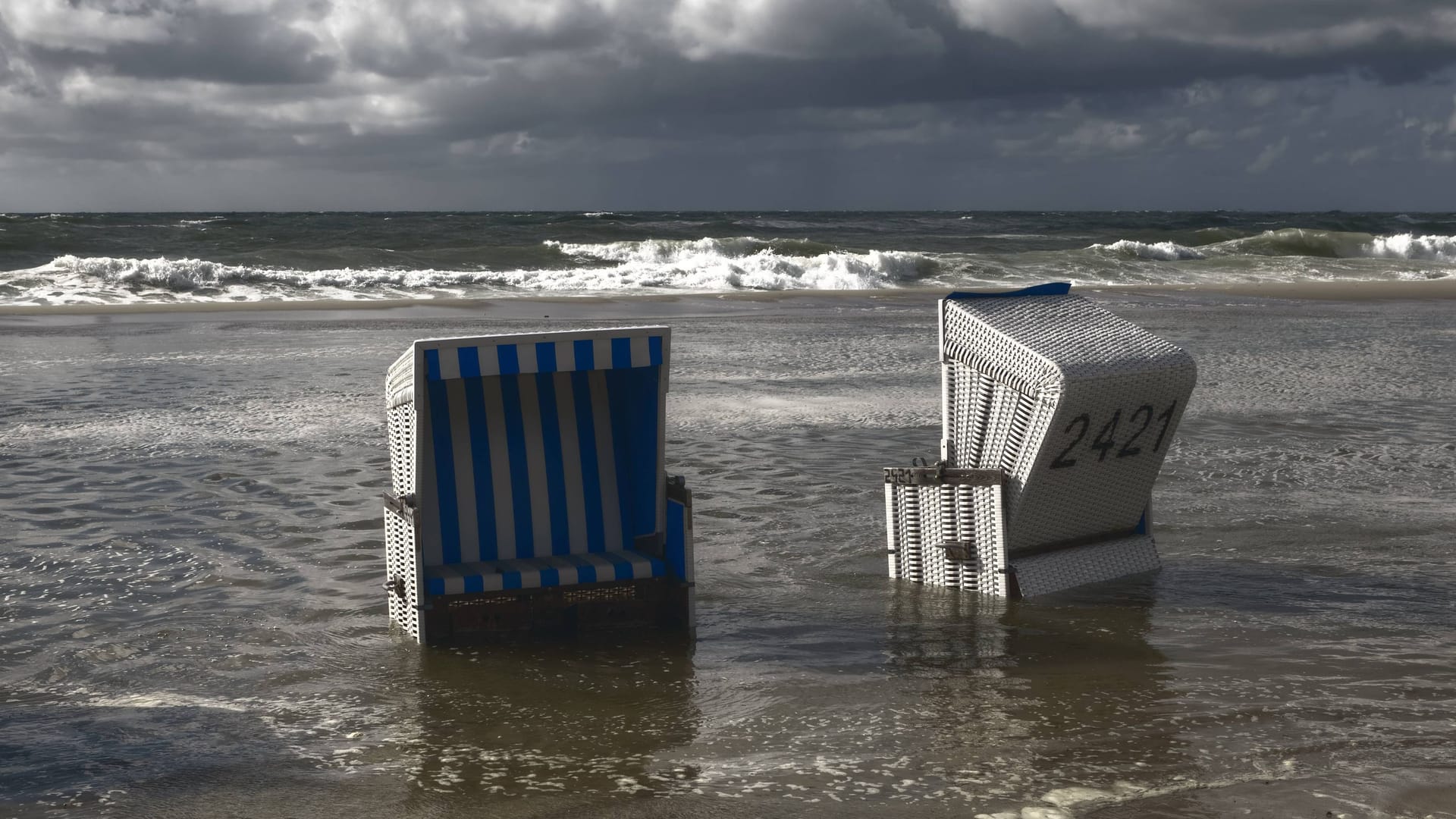 Strandkörbe während einer Sturmflut auf Sylt (Archivbild): Eine KI zeichnet ein düsteres, aber hoffnungsvolles Bild von der Zukunft der Urlaubsinsel.