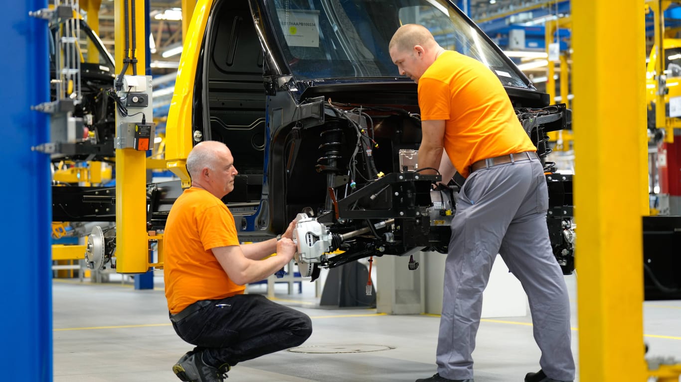 Arbeiter bauen ein elektrisches Auto zusammen (Symbolfoto): Die Autohersteller klagen über Auftragsmangel.