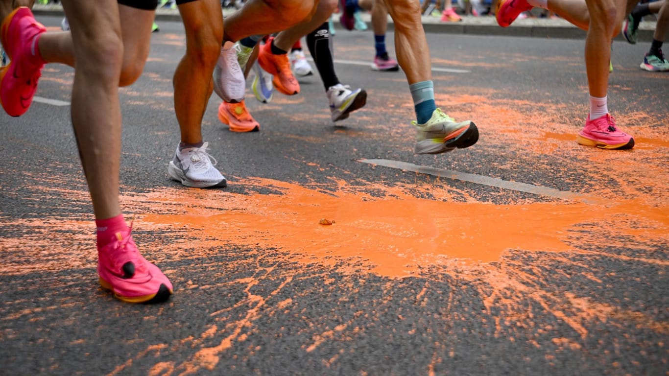Teilnehmer des Marathons laufen durch die Farbe: Sie wurde von der "Letzte Generation" auf die Strecke geschüttet.
