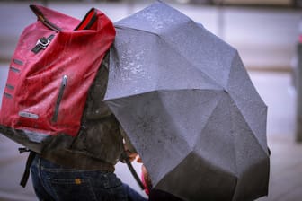 Mann schützt sich bei Starkregen und Sturm hinter einem Schirm vor dem Unwetter (Symbolbild): Zum Start der neuen Woche wird es ungemütlich im Norden Deutschlands.