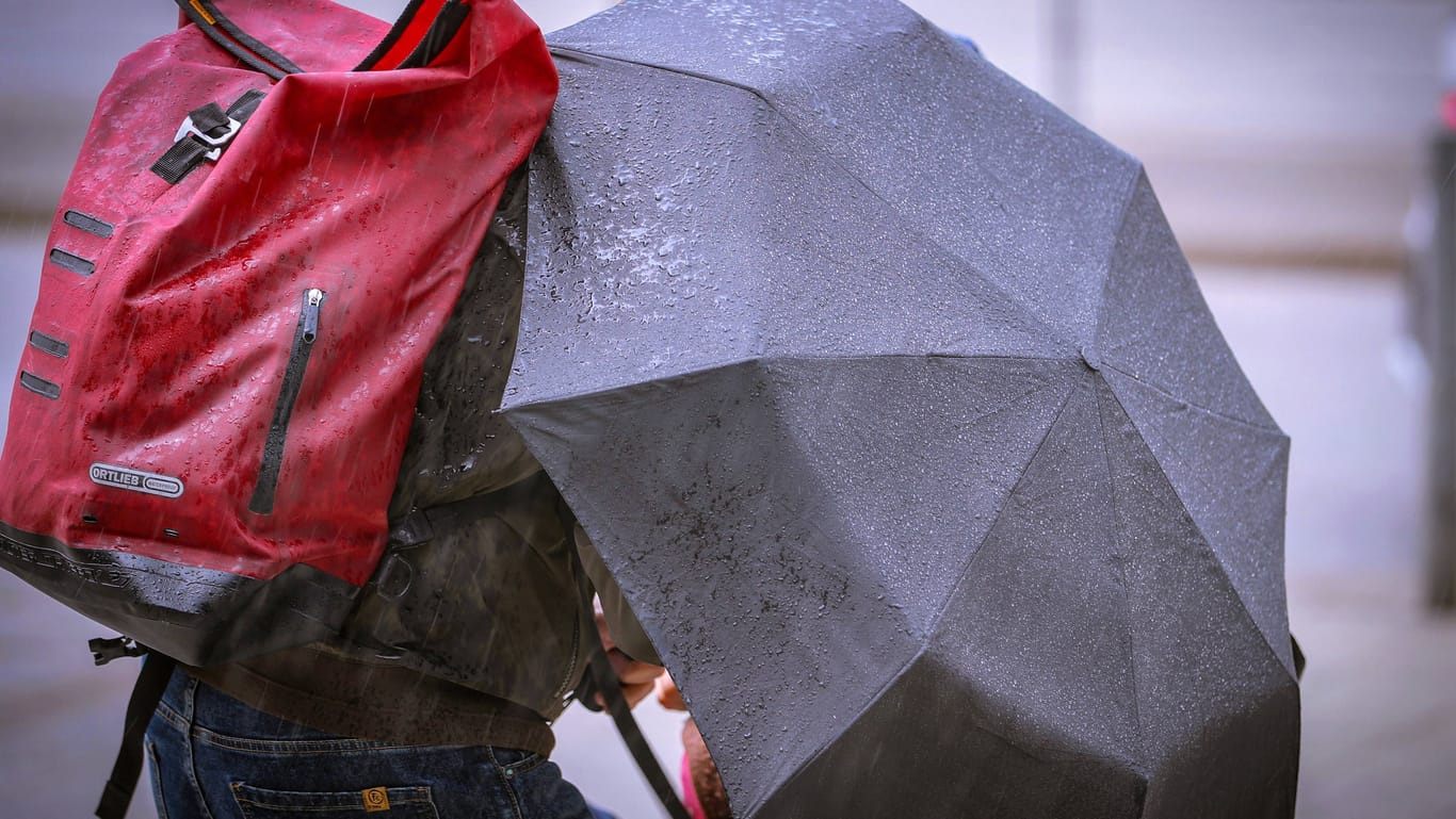 Mann schützt sich bei Starkregen und Sturm hinter einem Schirm vor dem Unwetter (Symbolbild): Zum Start der neuen Woche wird es ungemütlich im Norden Deutschlands.