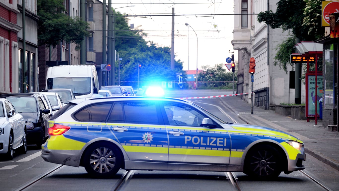Ein Polizeiauto steht vor einem abgesperrten Bereich: In Duisburg ist ein Mann an einer Tankstelle niedergestochen worden.