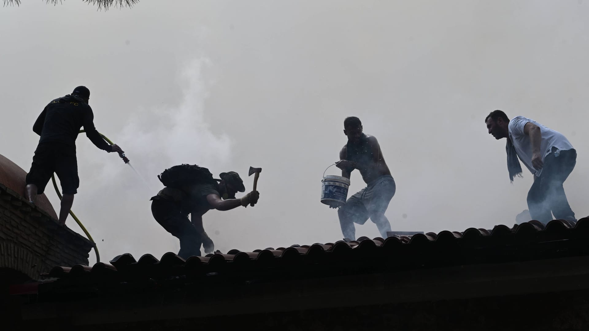 Anwohner und Feuerwehr bekämpfen einen Brand, der auf eine Kirche im griechischen Parnitha übergegangen ist.