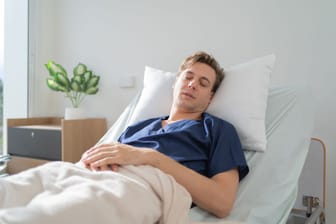 Ein Mann liegt in einem Krankenhausbett.