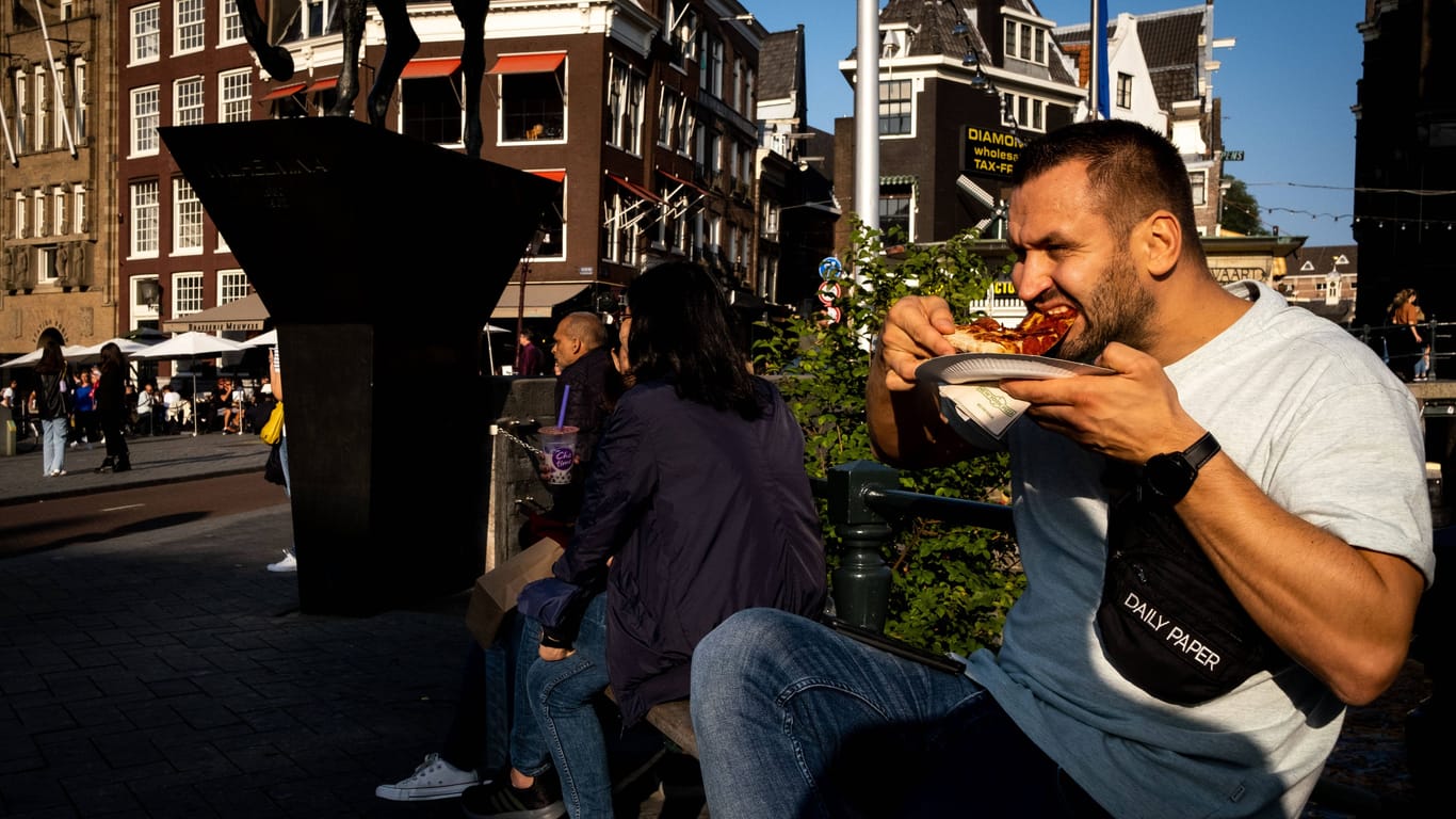 Touristen essen in Amsterdam auf der Straße (Archivbild).