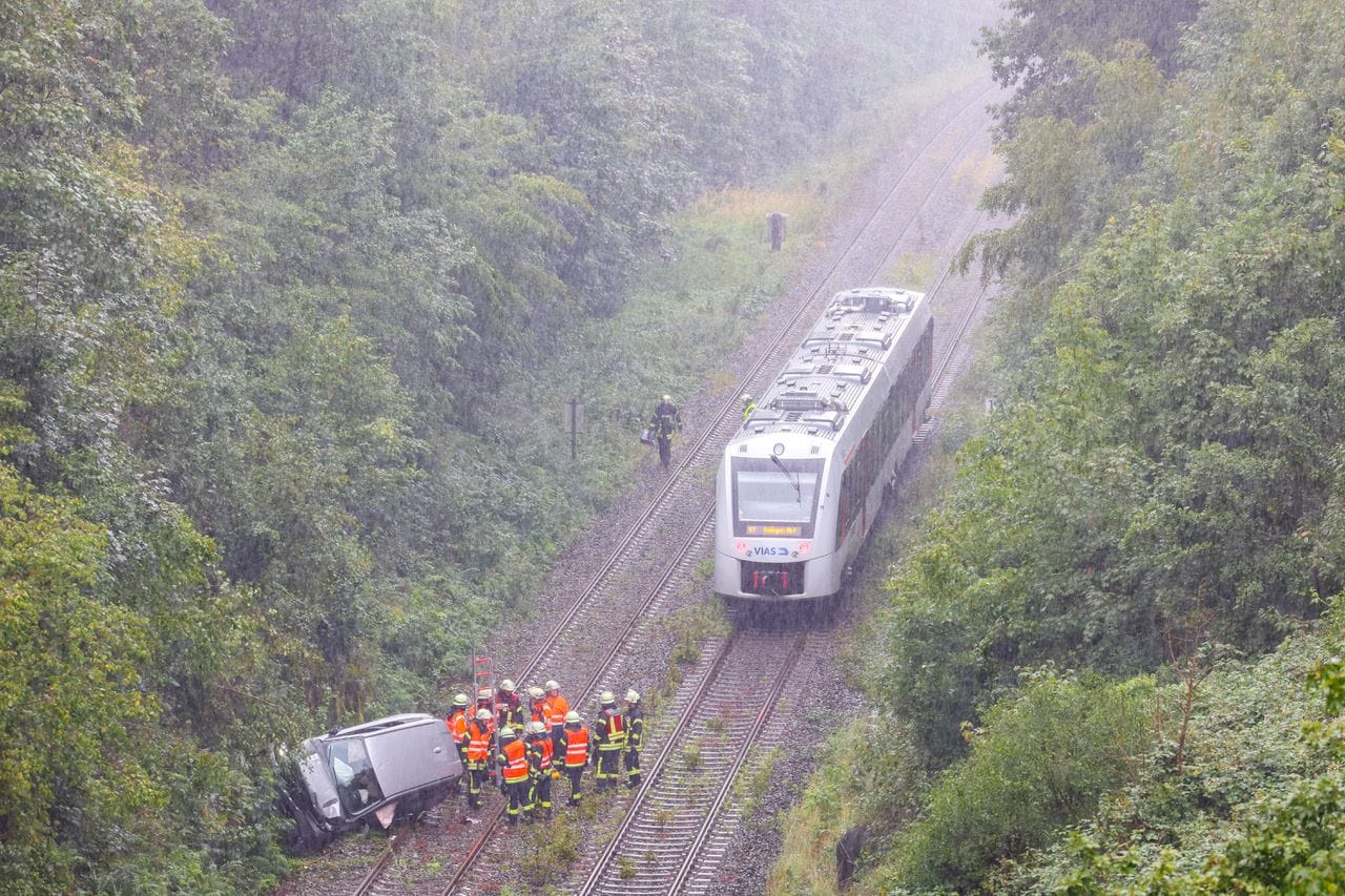 Der Wagen liegt seitlich auf der Bahnstrecke – knapp neben einer herannahenden S-Bahn.