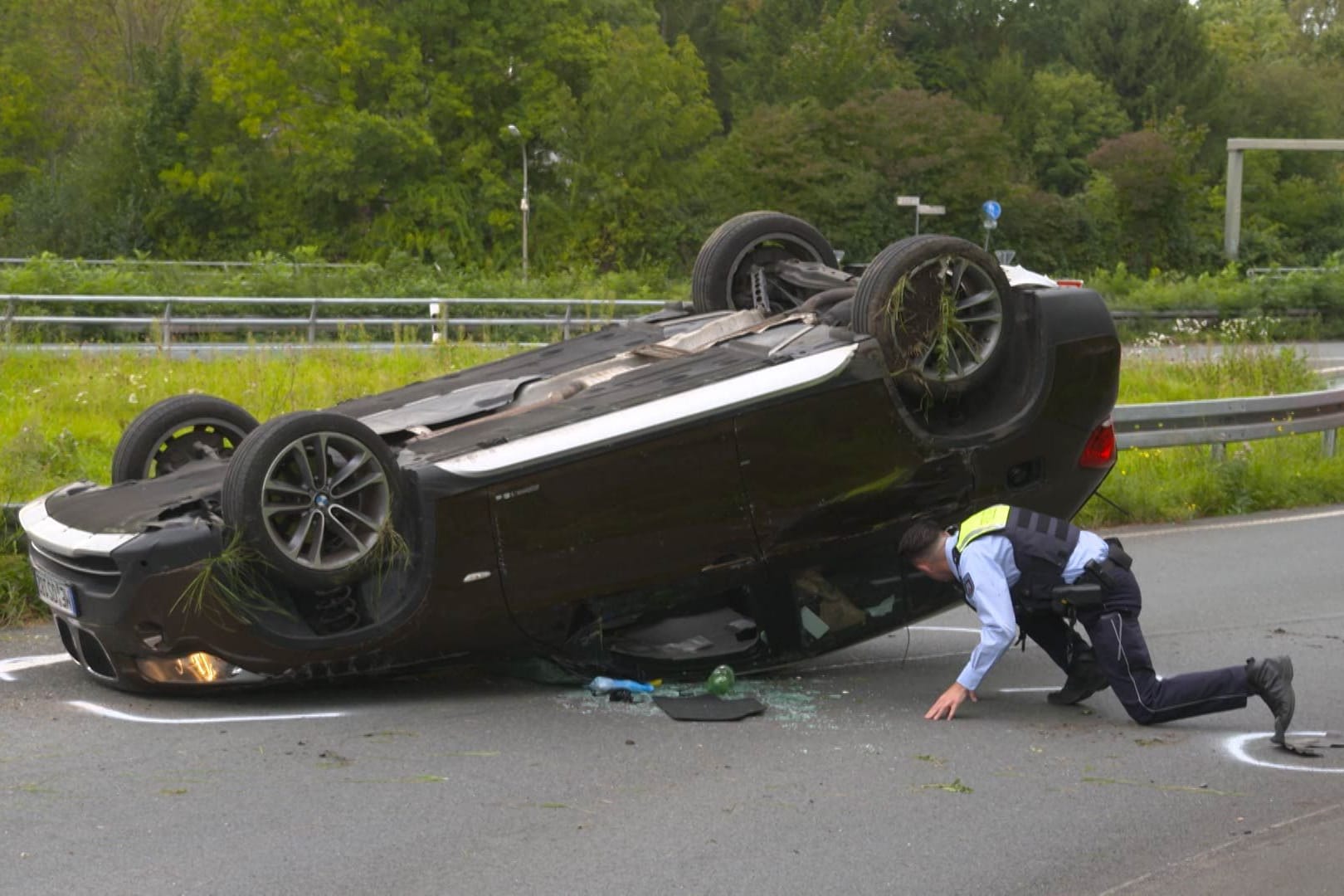 Ein Polizist untersucht das Unfallauto: Nach dem Überschlag landete das Auto auf dem Dach.