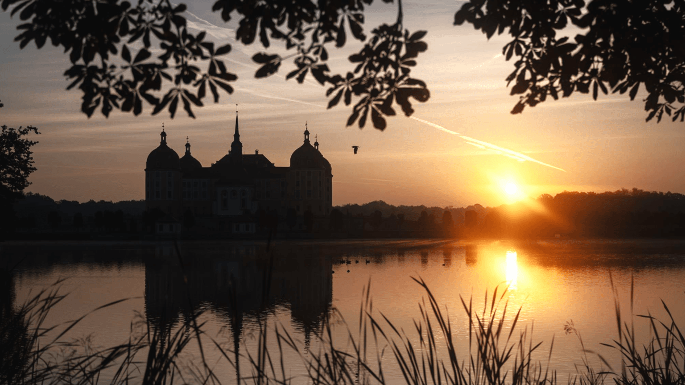 Die Sonne geht am Morgen hinter dem Schloss Moritzburg auf: So nutzen Sie den Spätsommer für Wochenendausflüge am besten.