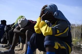Migranten sitzen bei großer Hitze in einer Notunterkunft auf der italienischen Mittelmeerinsel Lampedusa.