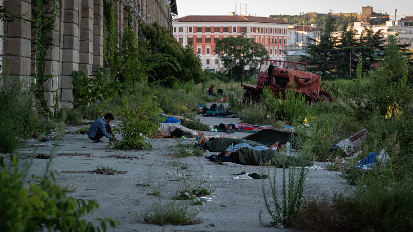 Migranten schlafen auf dem nackten Boden vor einer heruntergekommenen Lagerhalle in Triest (Archivbild).