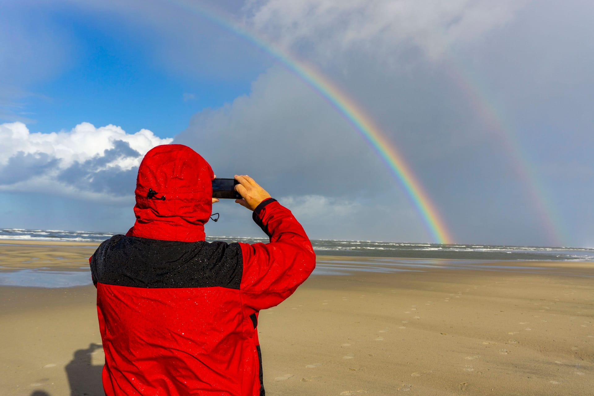 Ein Spaziergänger fotografiert einen Regenbogen auf der Insel Spiekeroog (Symbolbild): Der Sommer verabschiedet sich langsam.