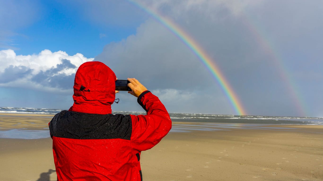 Ein Spaziergänger fotografiert einen Regenbogen auf der Insel Spiekeroog (Symbolbild): Der Sommer verabschiedet sich langsam.
