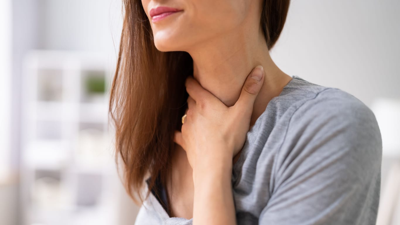 Frau fasst sich an den Hals: In manchen Fällen kommt ein Kloß im Hals von einer vergrößerten Schilddrüse.