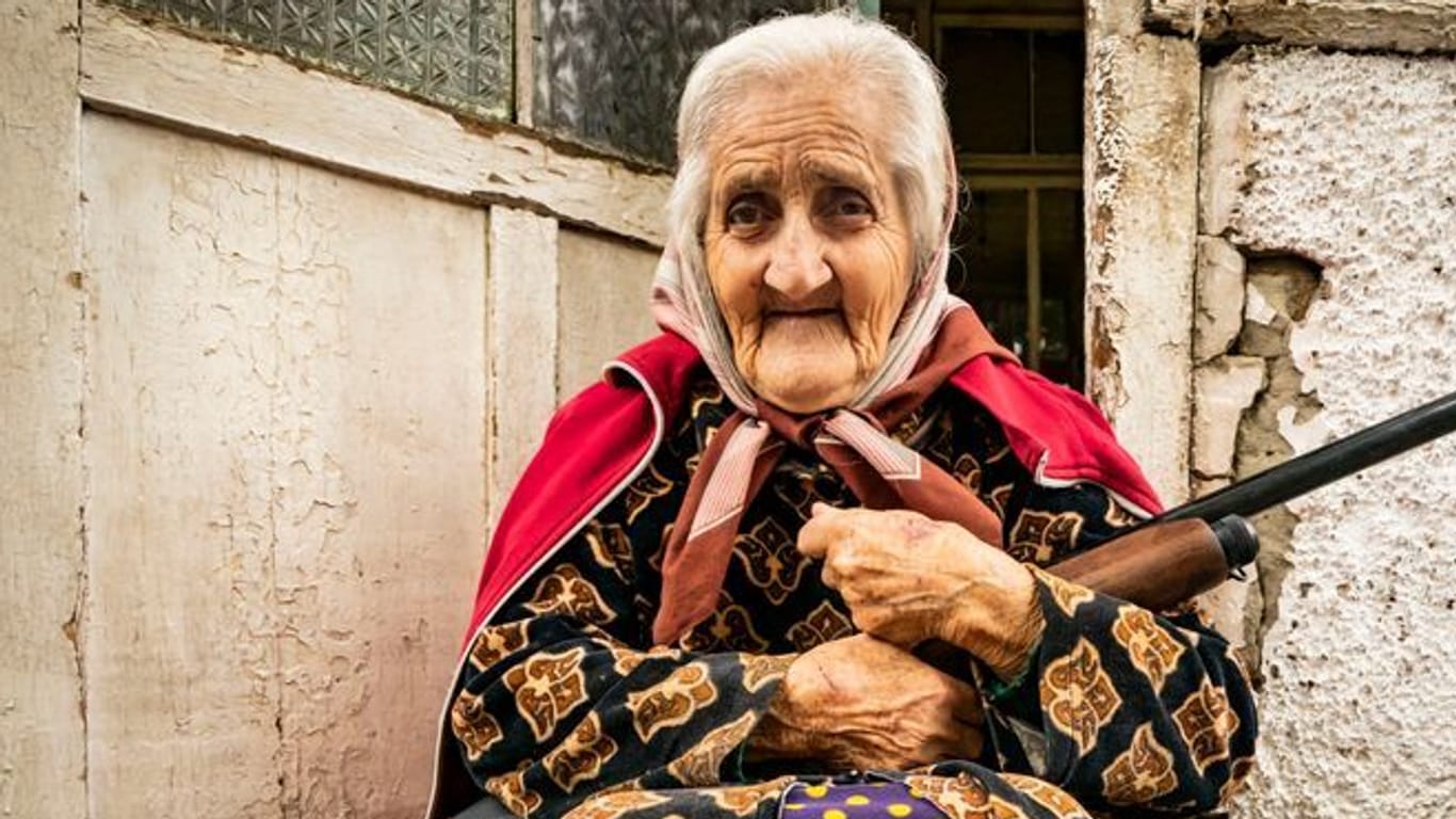Eine alte Frau sitzt mit einem Gewehr im Eingang ihres Hauses, während die aserbaidschanische Armee die Stadt Stepanakert unter Beschuss nimmt: Bereits zuvor war der Ort durch den Einsatz von Aserbaidschans Militär von der Außenwelt abgeschnitten.