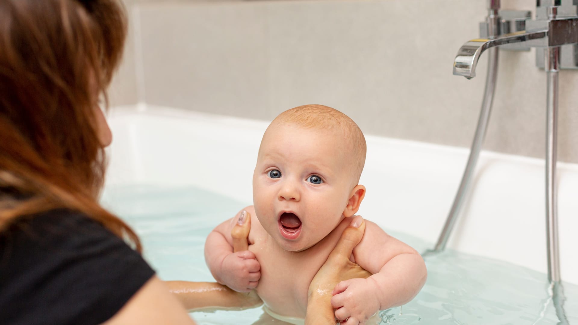 close up mother washing baby bathtub