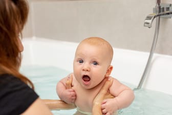 close up mother washing baby bathtub
