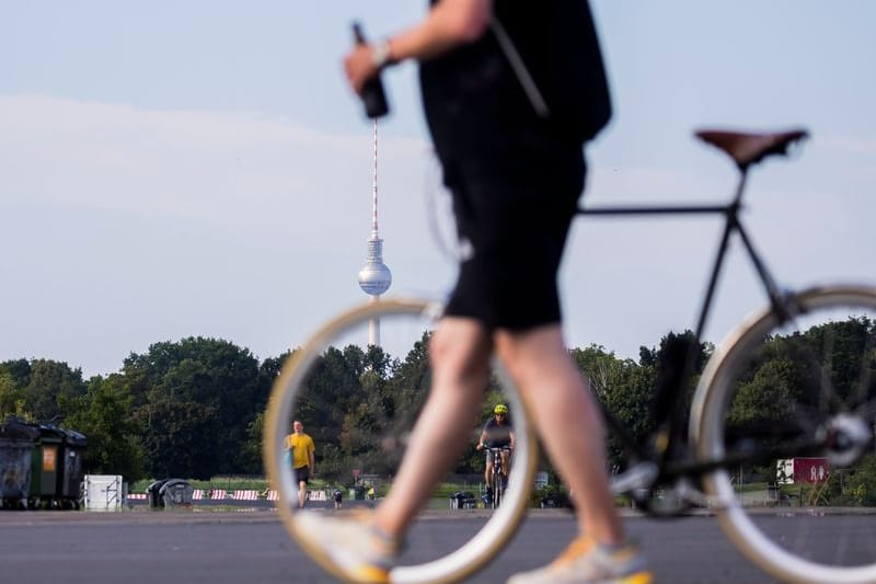 Ein Mann schiebt mit Flasche in der Hand sein Fahrrad über das Tempfelhofer Feld in Berlin