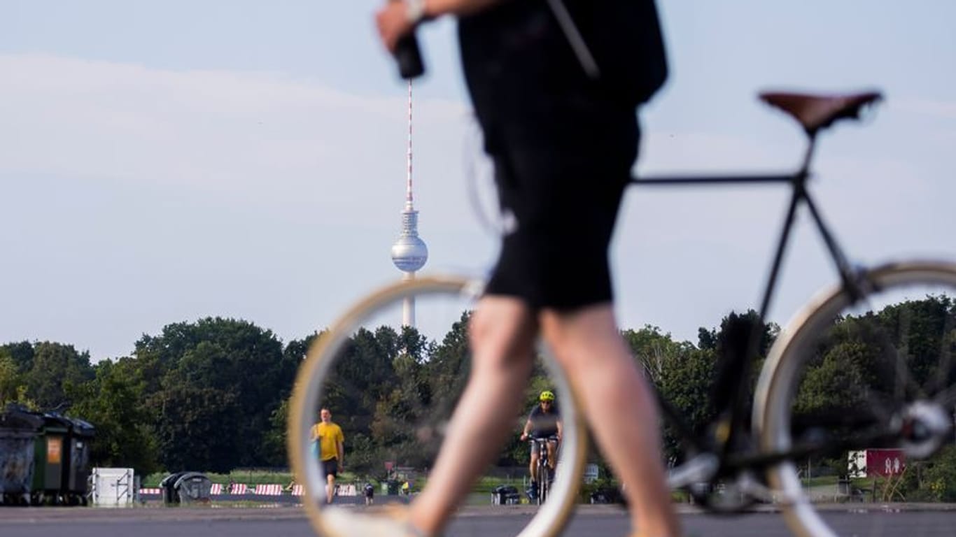Ein Mann schiebt mit Flasche in der Hand sein Fahrrad über das Tempfelhofer Feld in Berlin