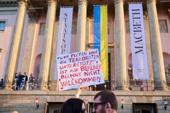 "Wer Putin und die Terroristen unterstützt ist auf Berliner Bühne nicht willkommen!" steht auf einem Plakat, das eine Demonstrantin vor der Staatsoper Unter den Linden hält. Zur Aufführung "Macbeth" mit Netrebko findet ein Protest gegen den Auftritt statt.