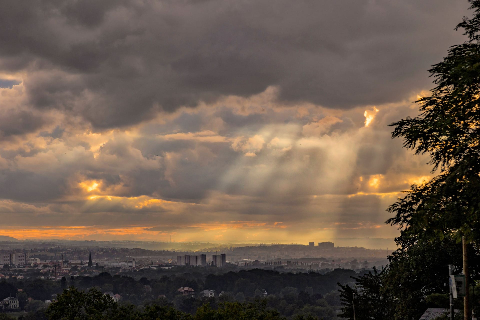 Die Sonne bricht über der Skyline von Dresden durch die Wolken.