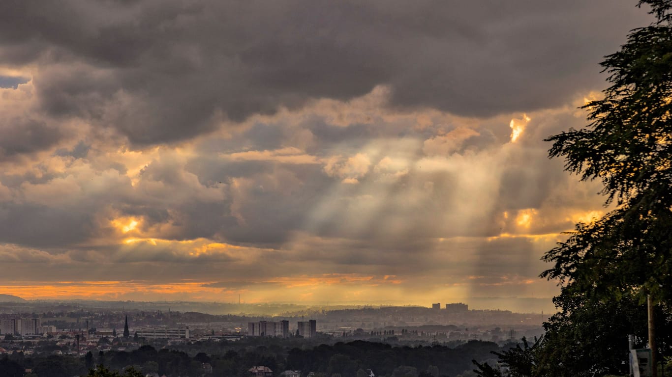 Die Sonne bricht über der Skyline von Dresden durch die Wolken.