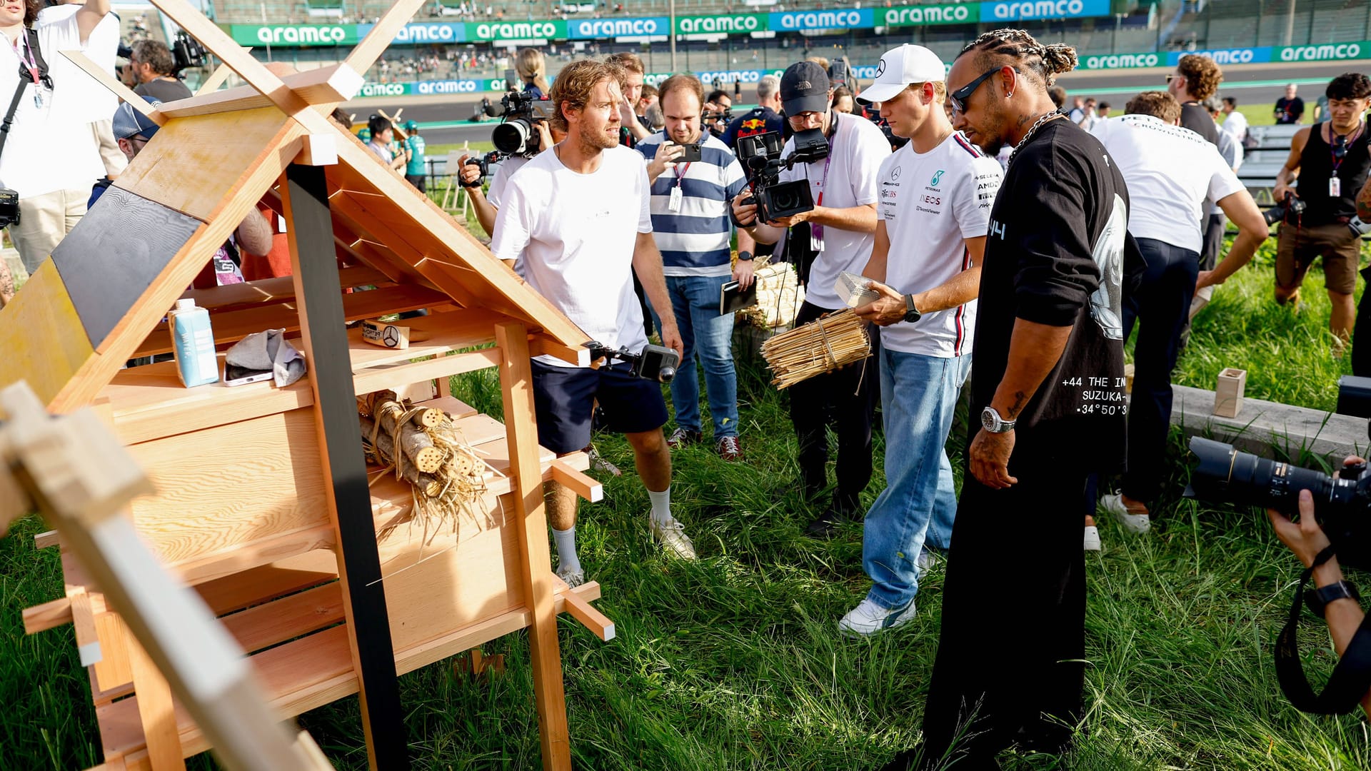 Sebastian Vettel (links) mit Mick Schumacher (Mitte) und Mercedes-Pilot Lewis Hamilton (rechts) beim Aufstellen der Insekten-Hotels.