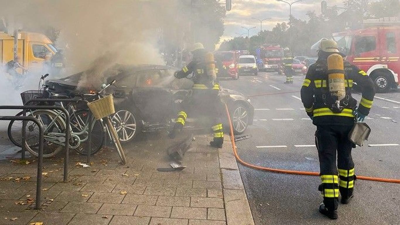 Einsatzkräfte der Berufsfeuerwehr München löschen den brennenden BMW.