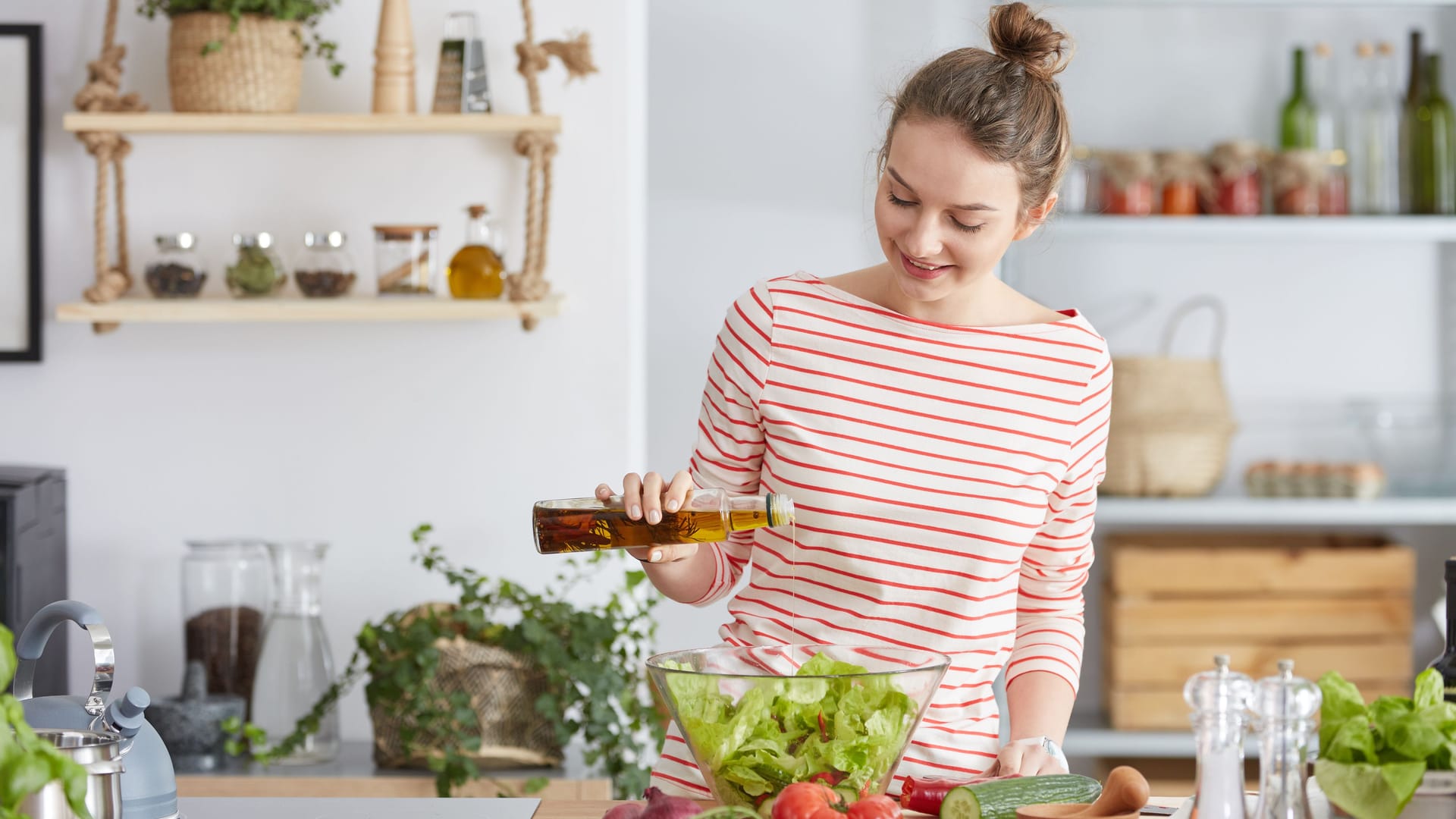 Eine Frau bereitet einen Salat mit Öl zu.