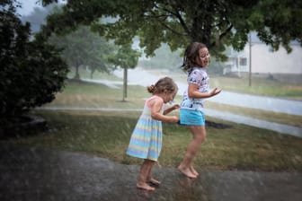 Kinder spielen im Freien im Regen (Symbolfoto): Das steht den Schülern wohl auch in den Herbstferien bevor.