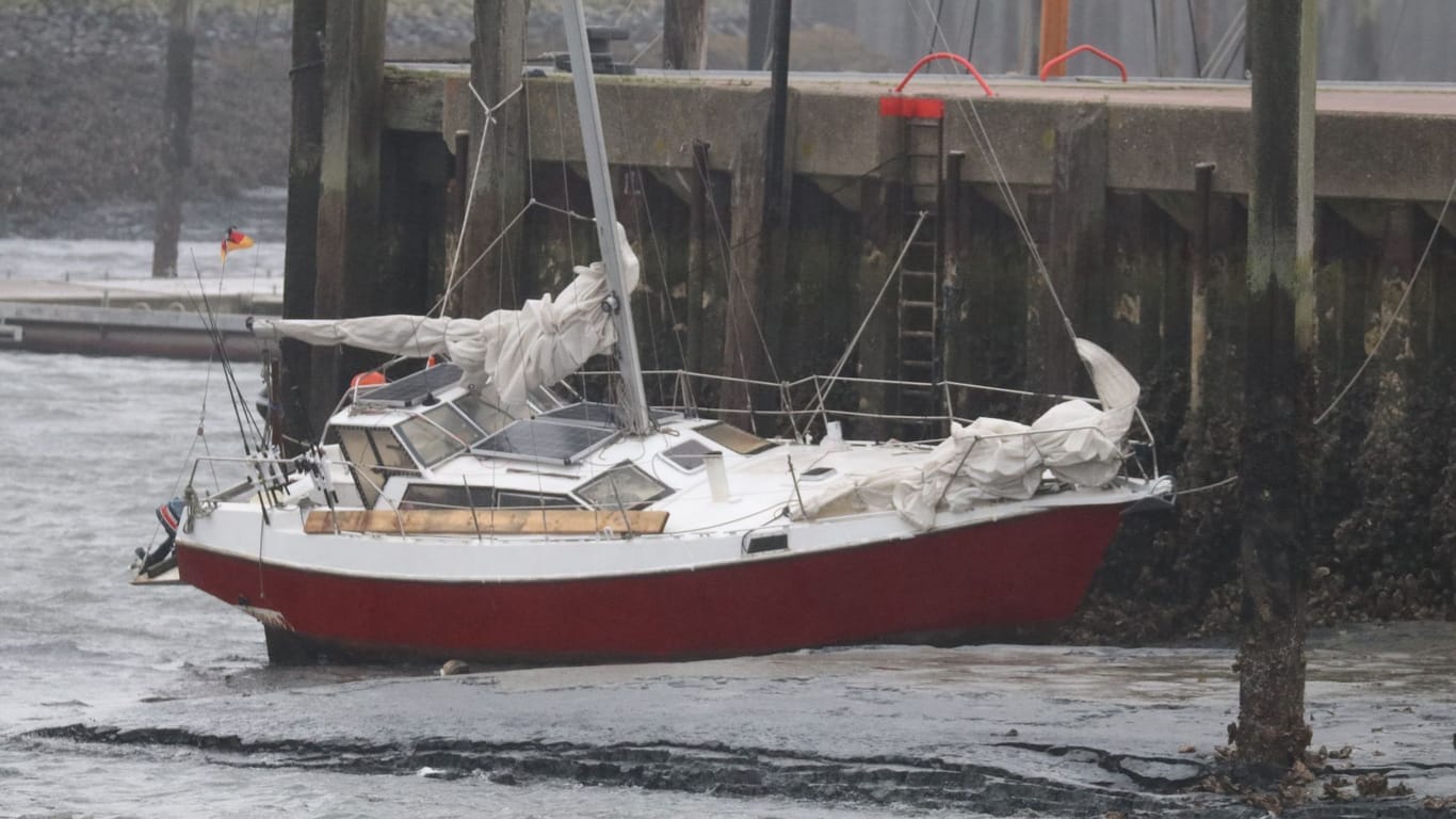 Ein Segelboot liegt bei extrem niedrigem Wasserstand bei Ebbe im Hafenbecken der Insel Norderney.