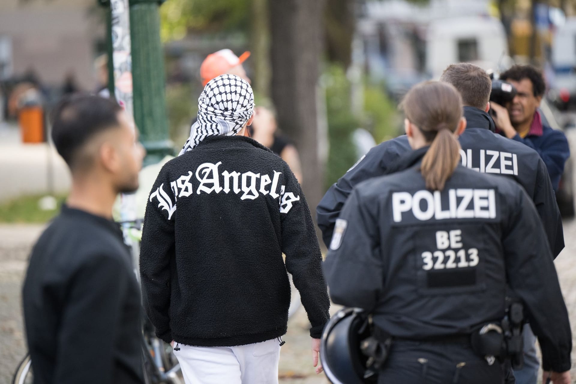 Polizeibeamte gehen im Stadtteil Neukölln neben einem Mann mit Palästinensertuch auf dem Kopf über den Richardplatz. Zuvor war eine Pro-Palästinensische Demonstration verboten worden.