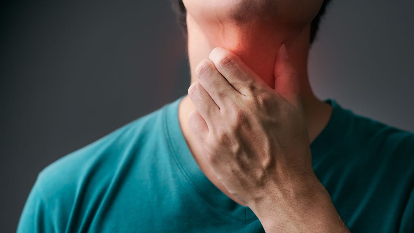 Ein Mann greift sich an den Hals: Eine refluxbedingte Speiseröhrenentzündung kann sich durch einen Kloß im Hals äußern.