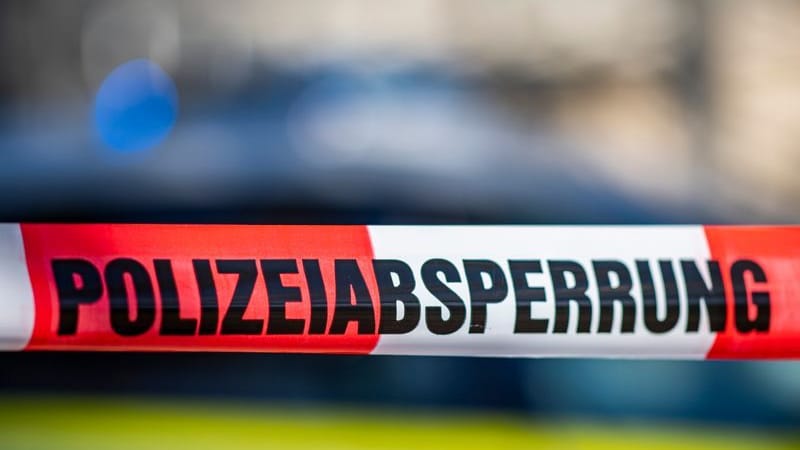 Ein Absperrband mit der Aufschrift «Polizeiabsperrung» ist vor einem Polizeiwagen aufgespannt.