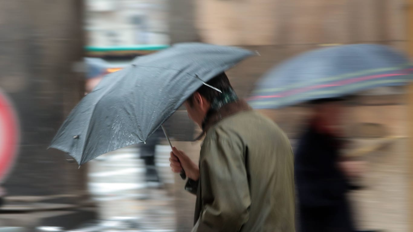 Ein Mann mit Regenschirm läuft über den Münchner Marienplatz (Archivbild): Das Wochenende im Süden und Südwesten droht ungemütlich zu werden.