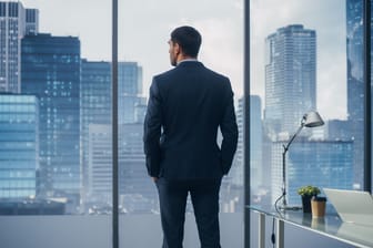 CEO schaut durchs Fenster auf die Skyline