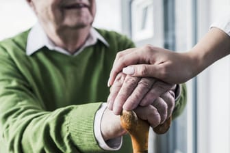 Eine Pflegerin hält die Hand eines Seniors (Symbolbild): Ein Mann gewann im Lotto. Von dem Gewinn sah er vor seinem Tod nichts.