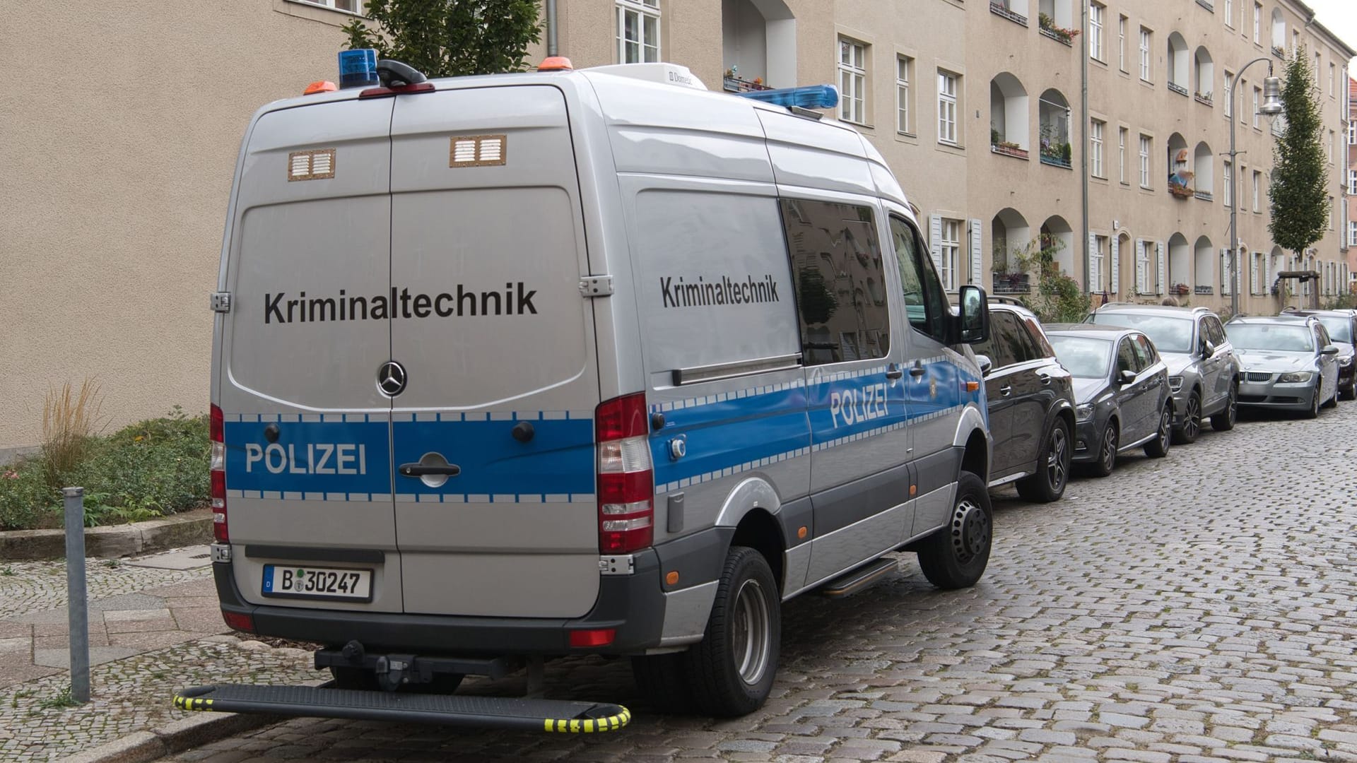 Ein Einsatzfahrzeug der Kriminaltechnik der Polizei steht vor einer Häuserzeile an der Kinzerallee im Berliner Stadtteil Köpenick. Dort wurden die Leichen einer Frau und eines Kindes gefunden.