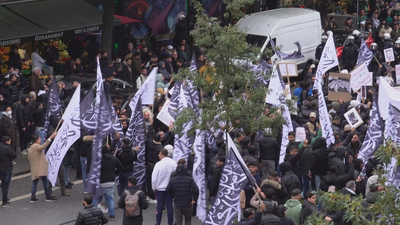 Demonstranten auf dem Hamburger Steindamm: Auf die schwarzen und weißen Flaggen ist das Glaubensbekenntnis im Islam, die Schahāda, gedruckt.