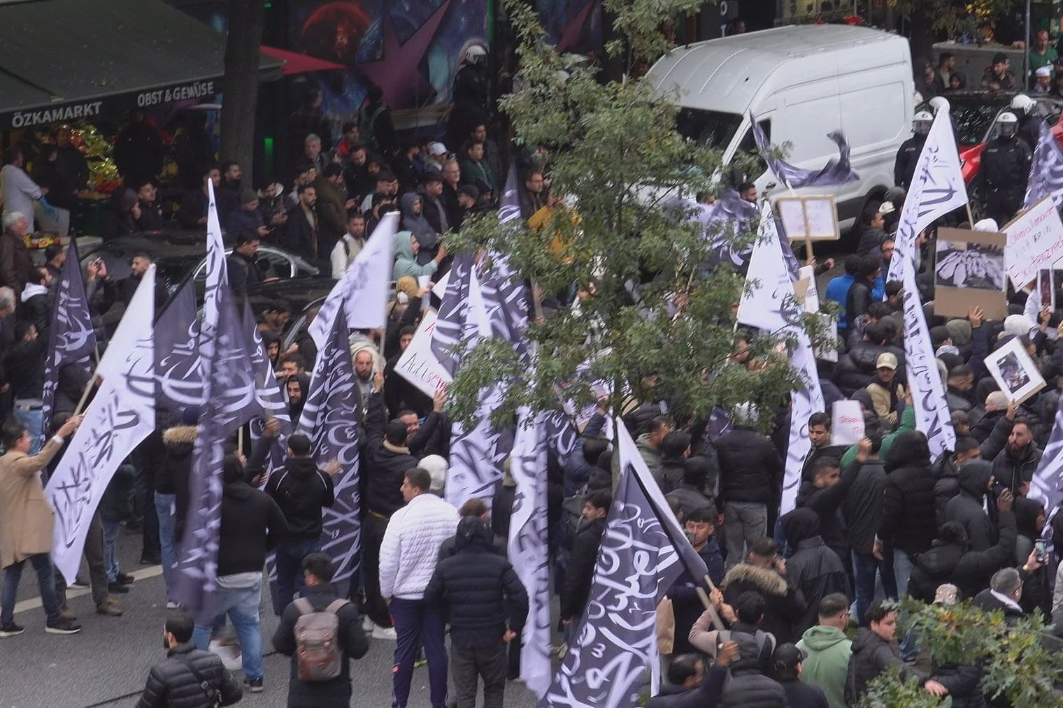 Demonstranten auf dem Hamburger Steindamm: Auf die schwarzen und weißen Flaggen ist das Glaubensbekenntnis im Islam, die Schahāda, gedruckt.