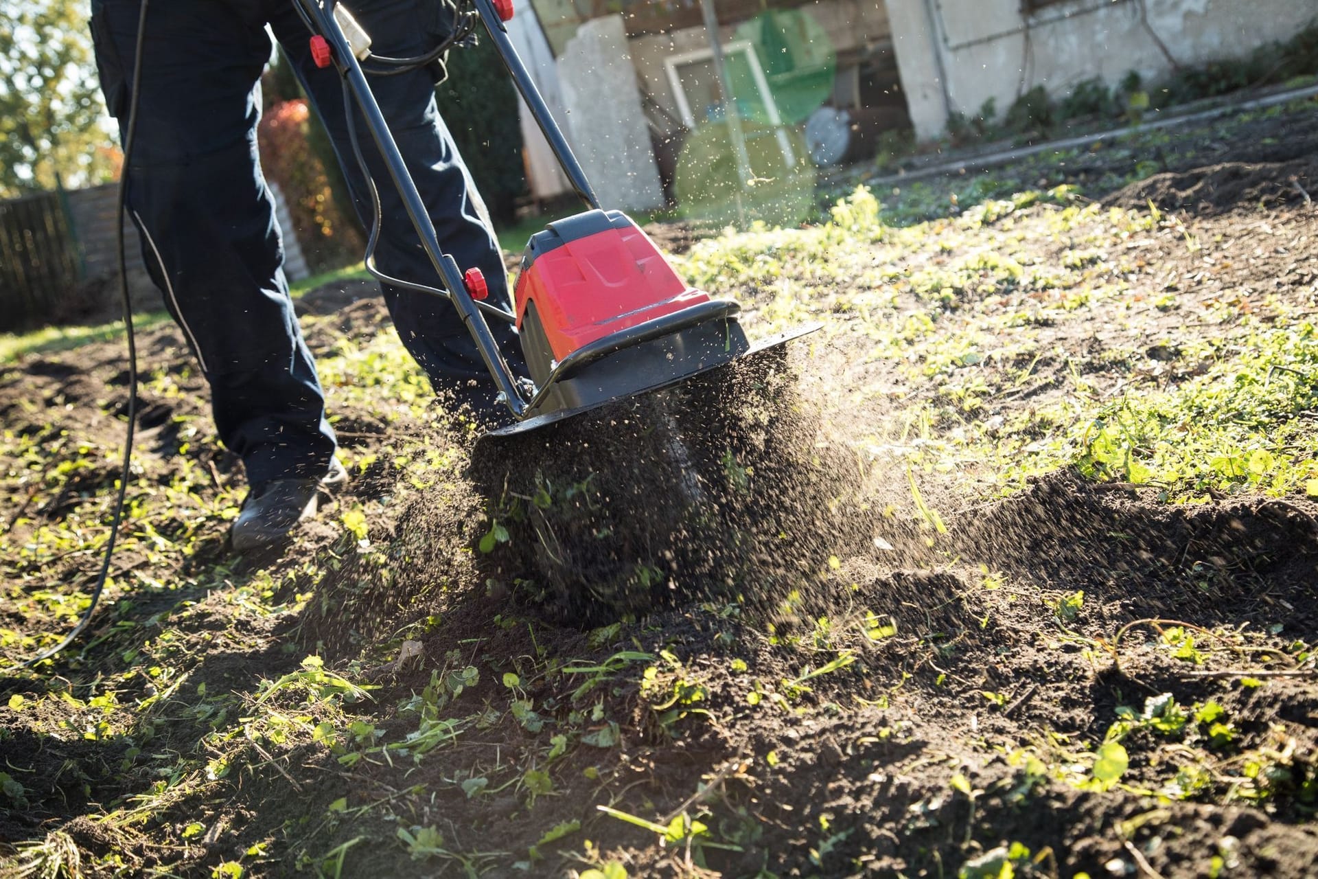 Eine Person bearbeitet Gartenboden